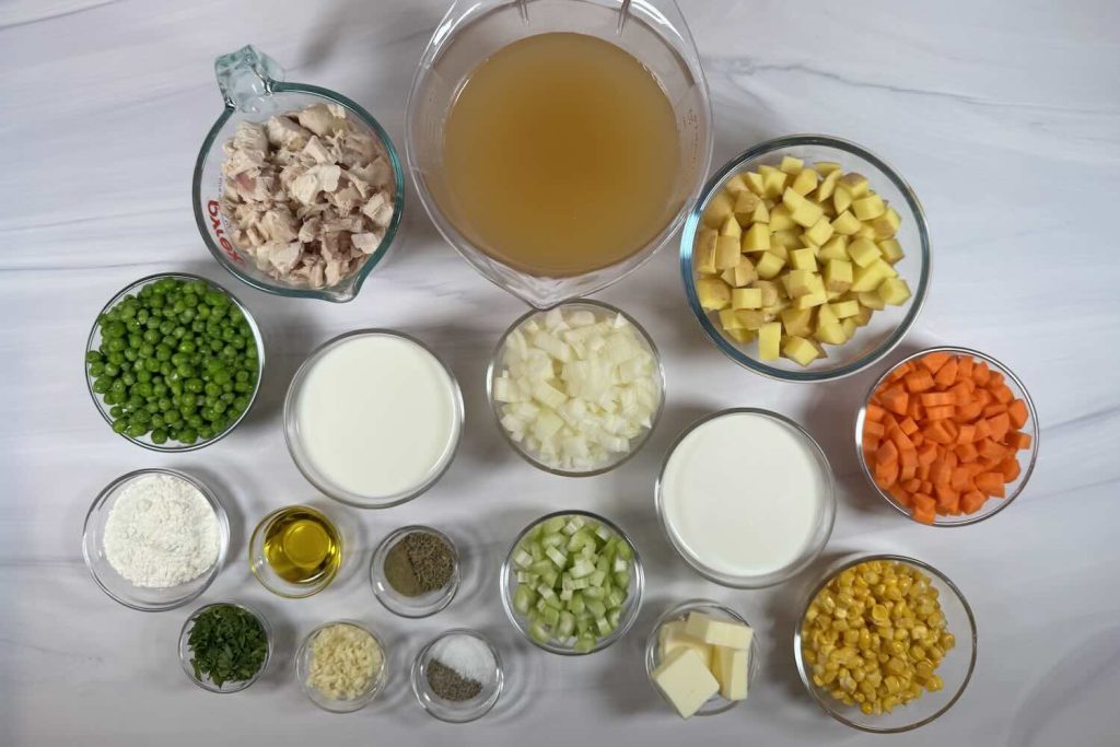 Ingredients for chicken pot pie soup including cooked chicken, potatoes, chicken broth, milk, heavy cream, onion, celery, carrots, peas, corn, butter, flour, garlic, olive oil, parsley, and seasonings.