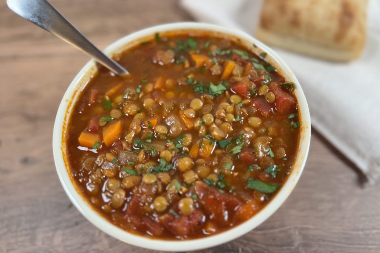 Bowl of easy one-pot lentil soup with carrots, celery, diced tomatoes, and herbs in a rich tomato-based broth, served with bread on the side.