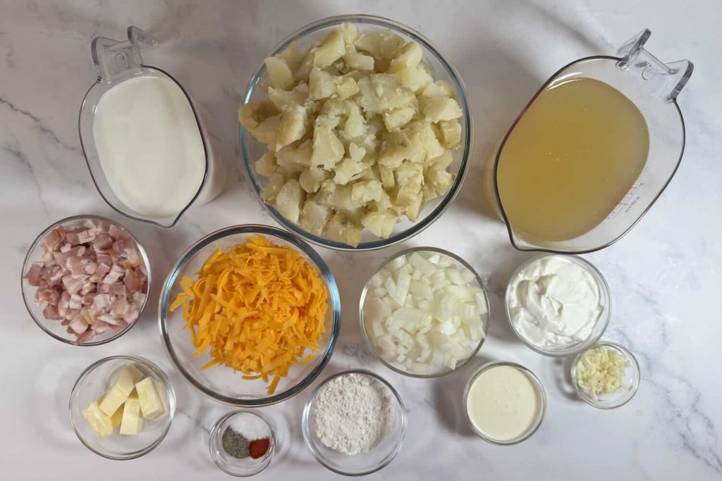 Ingredients for loaded baked potato soup including potatoes, chicken broth, milk, heavy cream, cheddar cheese, bacon, onion, garlic, butter, flour, sour cream, and seasonings.