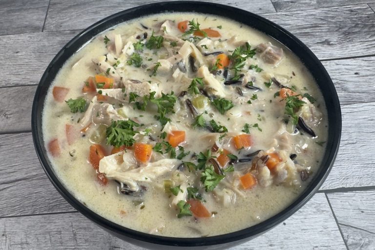 Bowl of creamy chicken and wild rice soup with shredded chicken, carrots, celery, and wild rice in a rich, creamy broth topped with fresh parsley.