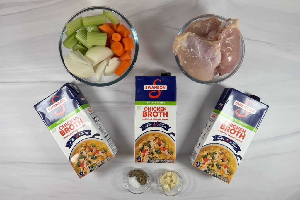 Ingredients for chicken soup base including raw chicken, carrots, celery, onion, garlic, chicken broth, salt, and black pepper.