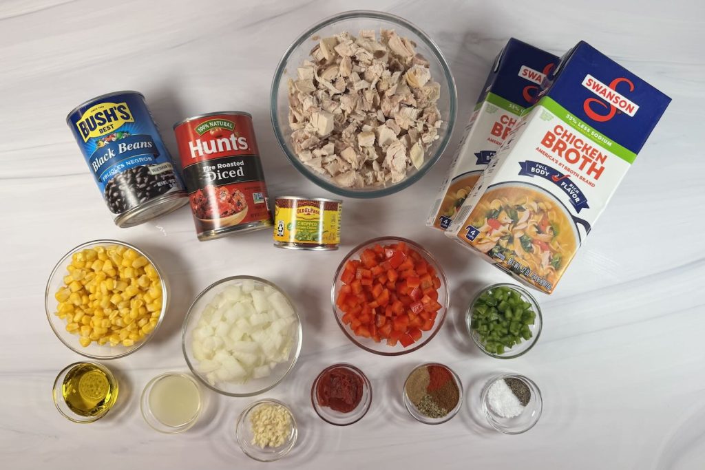 Ingredients for chicken tortilla soup including shredded chicken, black beans, fire-roasted tomatoes, corn, green chiles, bell pepper, onion, chicken broth, and seasonings.