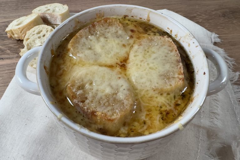 Classic French onion soup topped with toasted baguette slices and melted Gruyère cheese in an oven-safe soup crock.