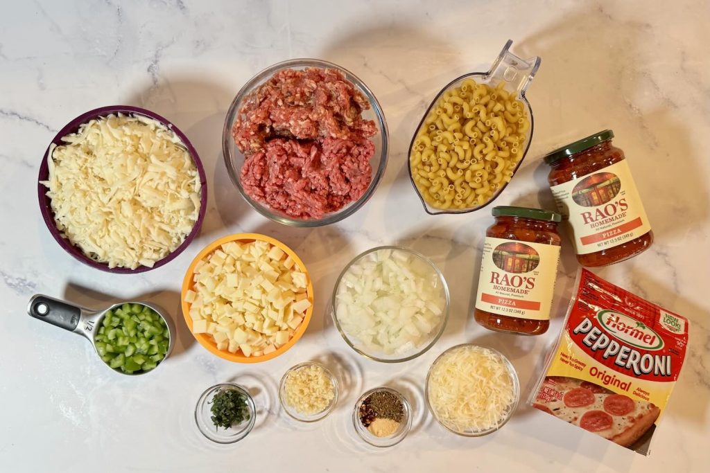 Ingredients for easy pizza casserole including ground beef, ground sausage, elbow macaroni, pizza sauce, pepperoni, shredded mozzarella, diced provolone, onion, green bell pepper, Parmesan, garlic, basil, and seasonings.